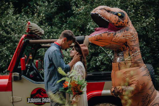 a bride and a groom look at each other by a trex and vehicle